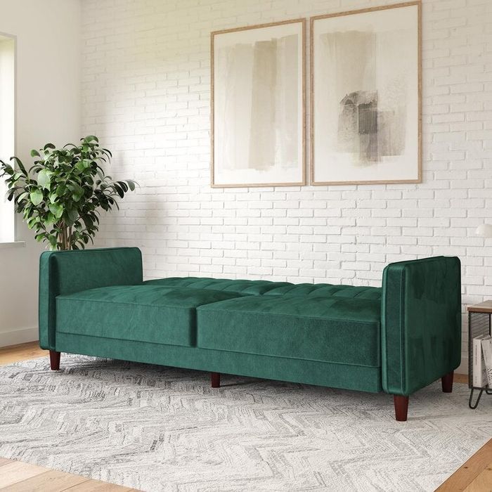 The green velvet sofa fully reclined, turning into a cozy sleeper