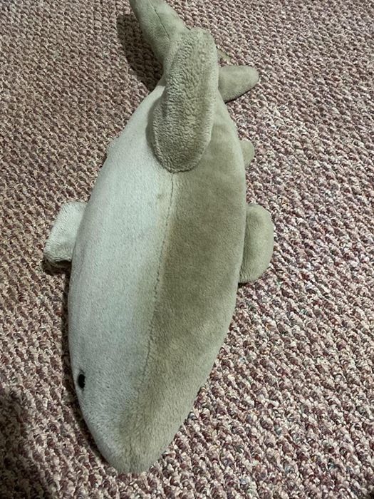 A reviewer posted a split-image of a stuffed shark toy, highlighting one half as dirty and the other half perfectly clean after using the carpet cleaning device.