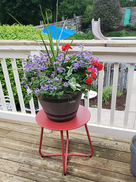 A reviewer’s photo showing a red table with a pot of flowers on it, sitting on a deck.