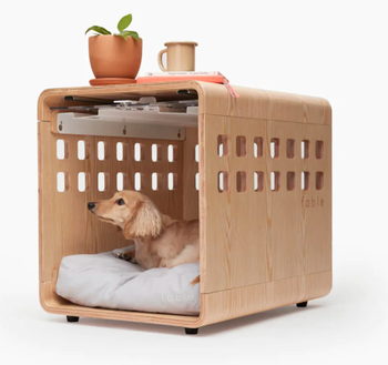 A small dog is inside the crate, looking cozy.