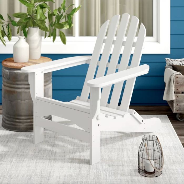 A white Adirondack chair placed on a beautifully decorated deck, enhancing the outdoor ambiance with its relaxed charm.