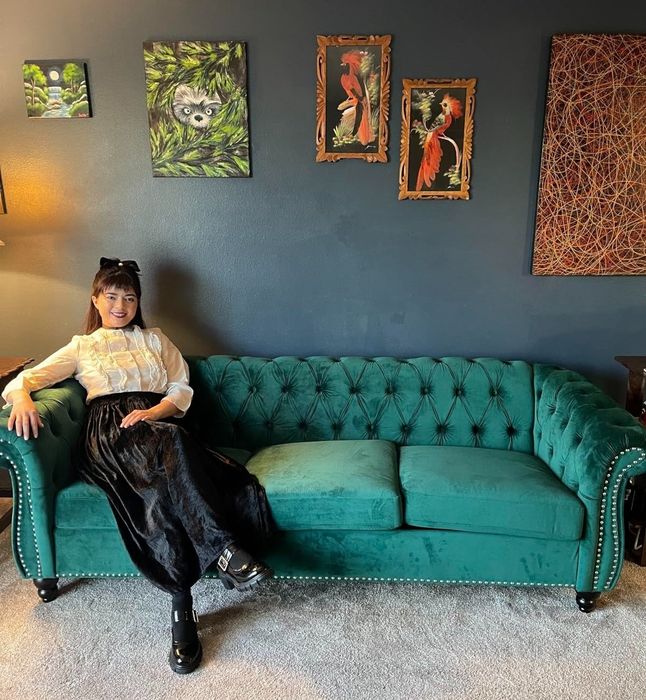 A reviewer’s photo shows a person sitting on a green couch