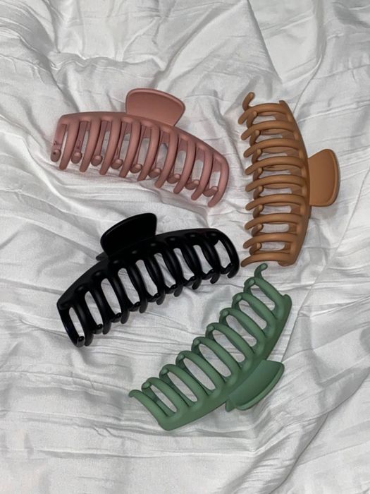 A set of four clips in tan, black, green, and pink shown by the reviewer