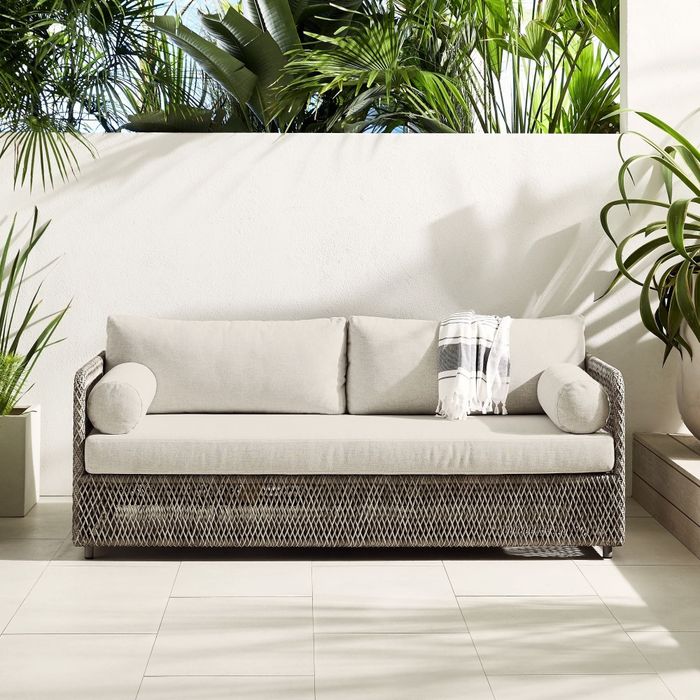 A gray rattan and white sofa is shown