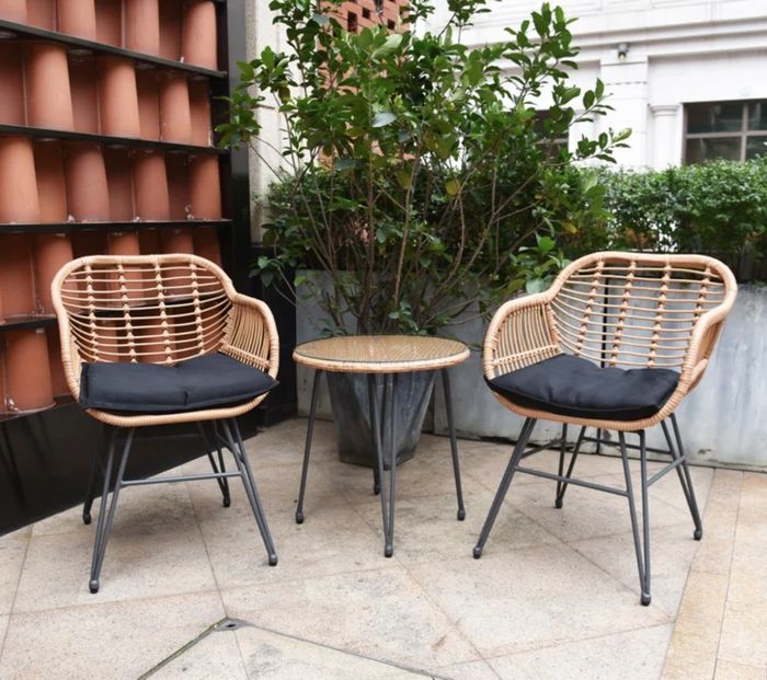 A tan wicker set complete with black cushions, designed for comfort and style.