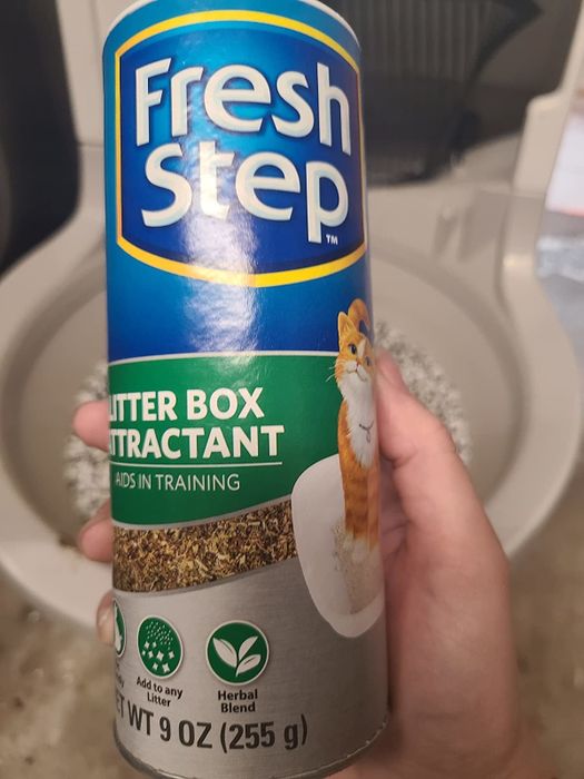 a reviewer showcasing the container of litter attractant