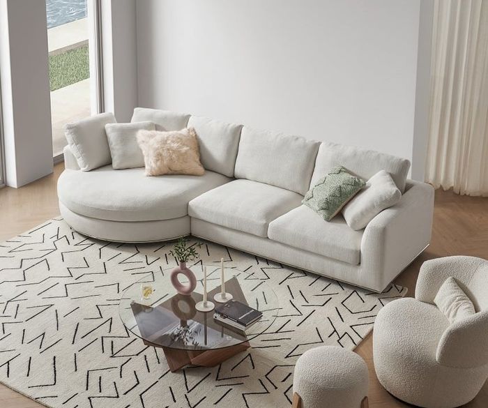 A white-toned sectional with a round chaise is showcased in a modern living room setting.