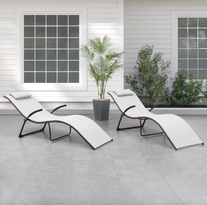 The light grey, swooping chaises nestled in a beautifully curated outdoor space, offering both form and function.