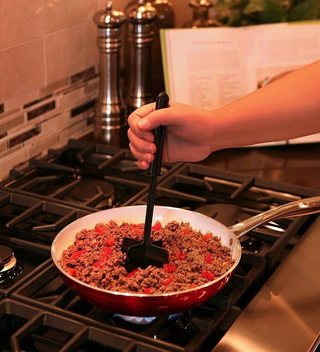 A close-up of a hand using the sleek black chopper to break up ingredients.