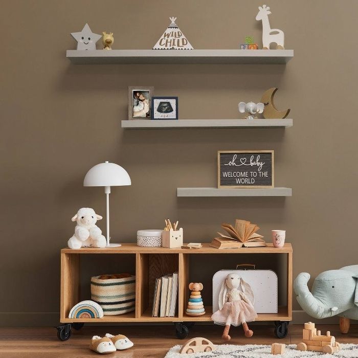 Three stylish shelves mounted above a cabinet filled with toys.