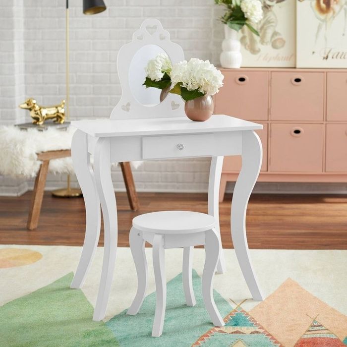A small white vanity set paired with a matching stool, sitting in a cozy bedroom.
