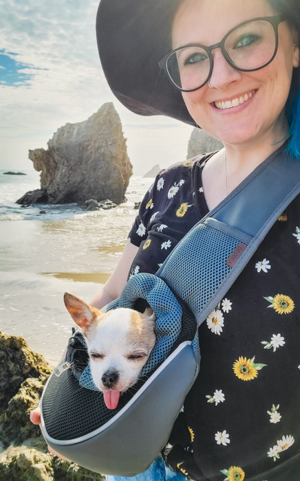 Reviewer enjoying the beach with their dog in a sling carrier
