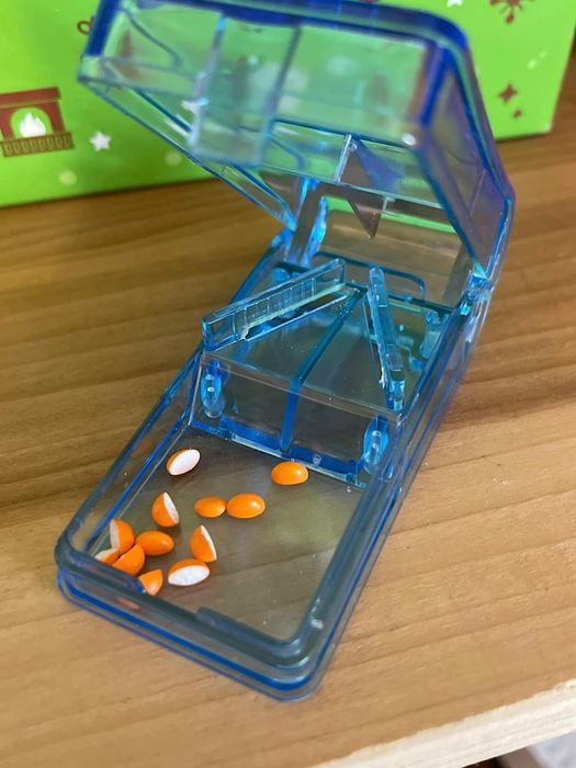 A blue pill cutter containing several neatly divided pills