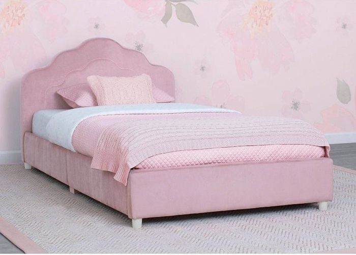 A pink upholstered bed nestled in a room with pink floral wallpaper and a soft pink rug.