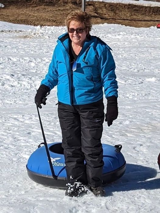 A reviewer enjoys snow tubing while wearing a blue ski jacket, keeping warm and stylish in the winter fun.