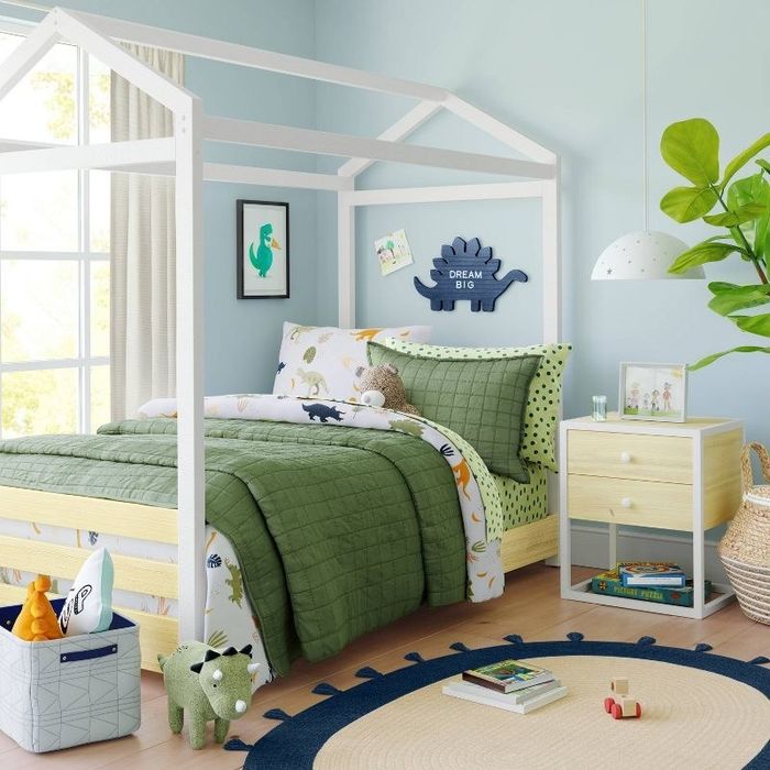 A child's bedroom thoughtfully arranged with bedding, toys, and a wooden nightstand.