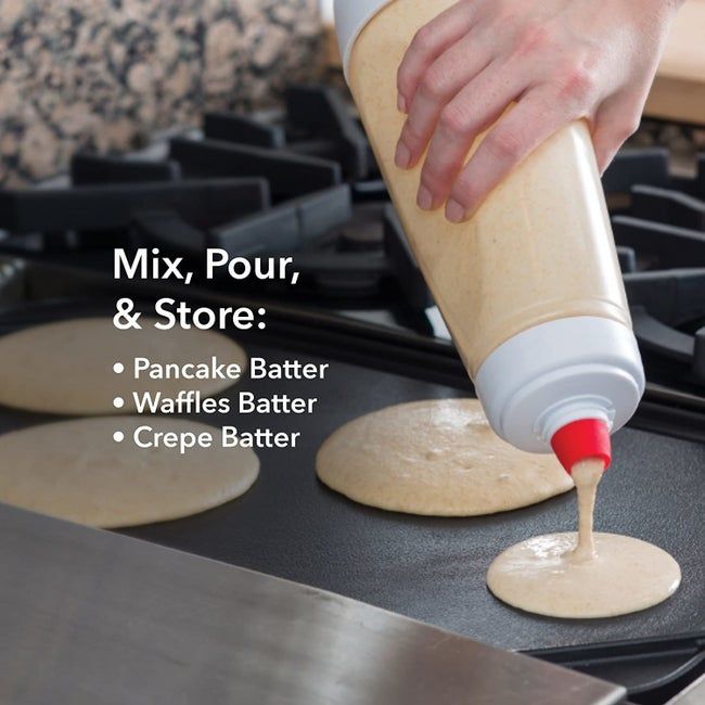 A hand holds a batter-filled bottle, pouring perfect pancake circles onto a sizzling griddle.