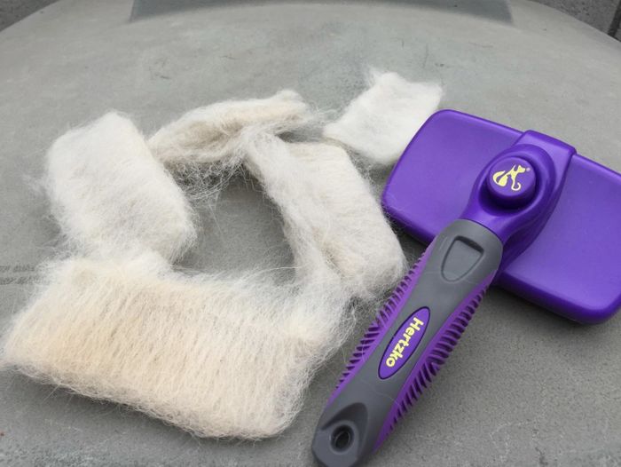 A purple Hertzko self-cleaning brush surrounded by piles of fur