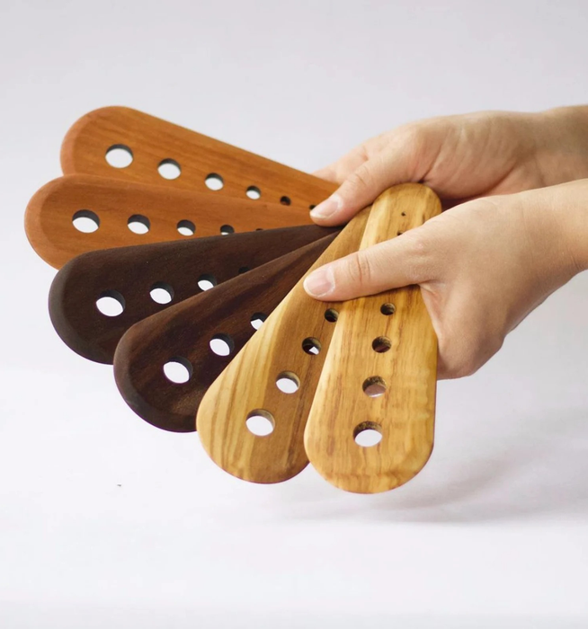Hands holding the herb strippers crafted in three types of wood