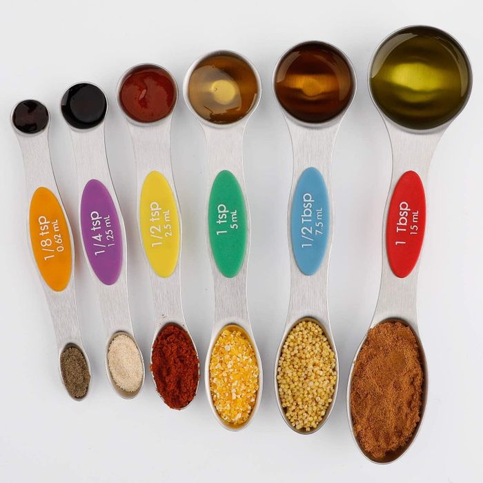 A set of measuring spoons with various ingredients in each one