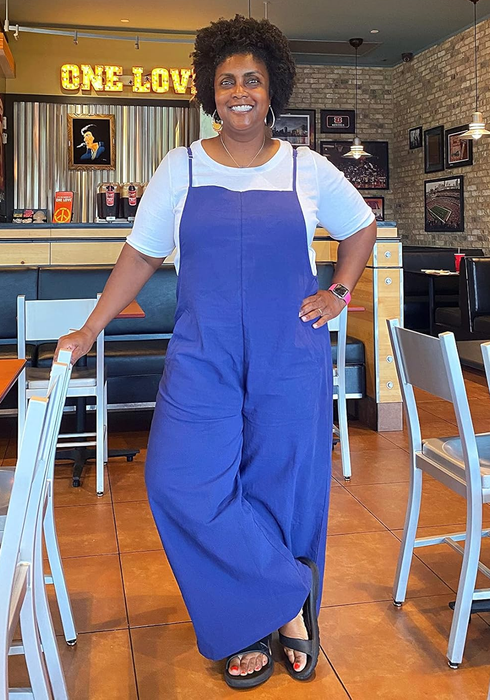 A reviewer dons a blue wide-leg jumpsuit paired with a white tee underneath.
