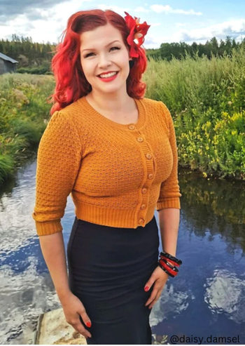 A model is wearing an orange cropped cardigan.