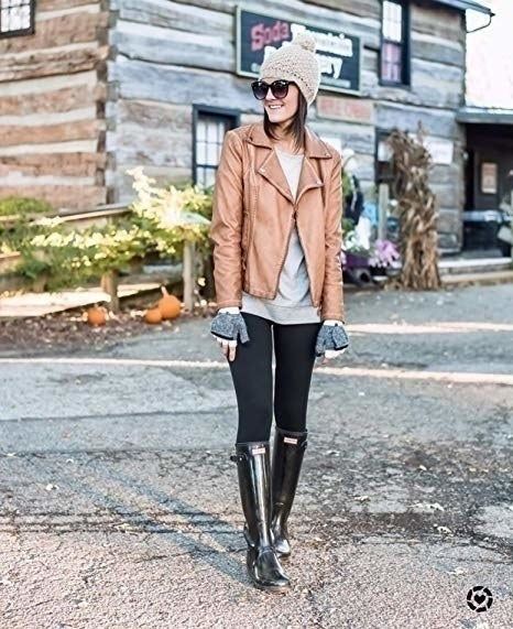 A model shows off the black leggings paired with rain boots and a leather jacket.