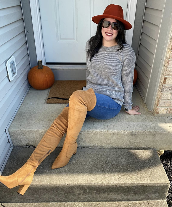 A reviewer is seen wearing brown thigh-high boots.