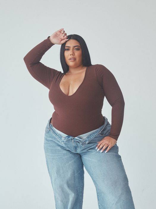 A model showcases a deep V-neck brown long-sleeve bodysuit paired with relaxed-fit jeans, creating a chic casual outfit.