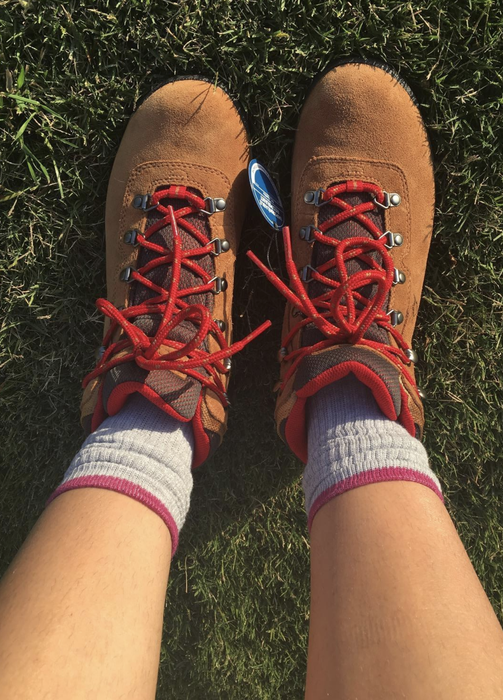 A reviewer wearing brown boots with red laces, showcasing their style.