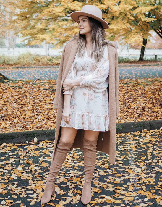 A reviewer pairs tan over-the-knee boots with a white dress, tan jacket, and matching hat.
