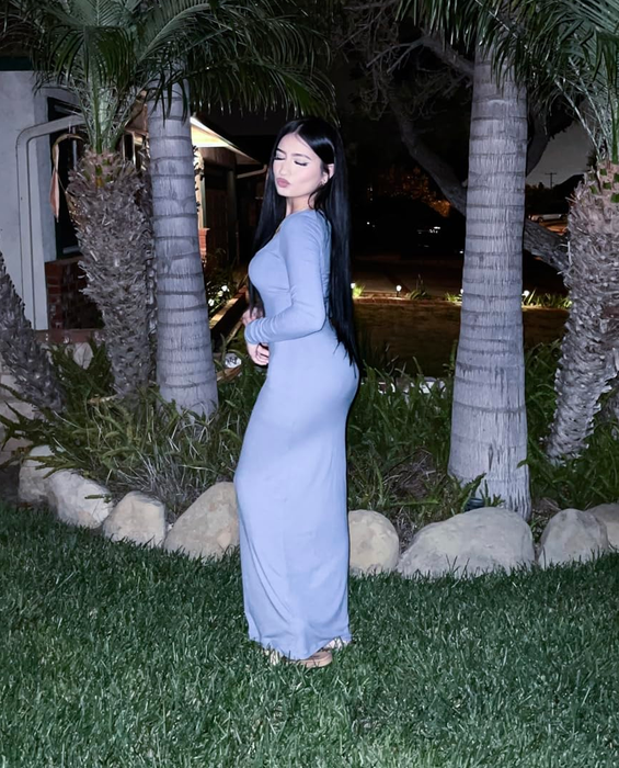 Side view of a reviewer wearing a long-sleeve blue maxi bodycon dress.