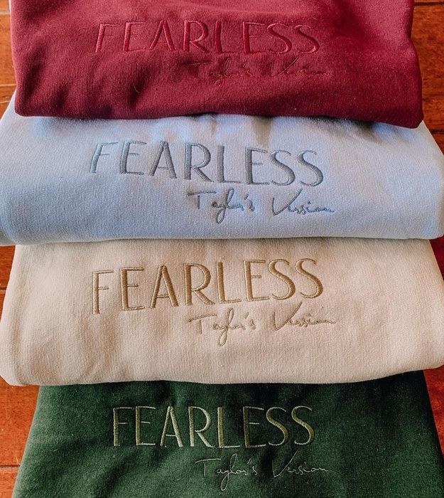 A pile of embroidered sweatshirts, each adorned with the words