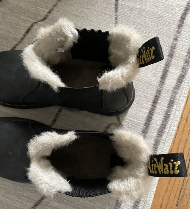 A reviewer showcases the black boots featuring faux fur lining for added warmth.