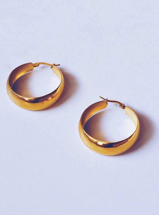 A close-up shot of two gold hoop earrings resting on a flat surface, featured in a Shopping article.