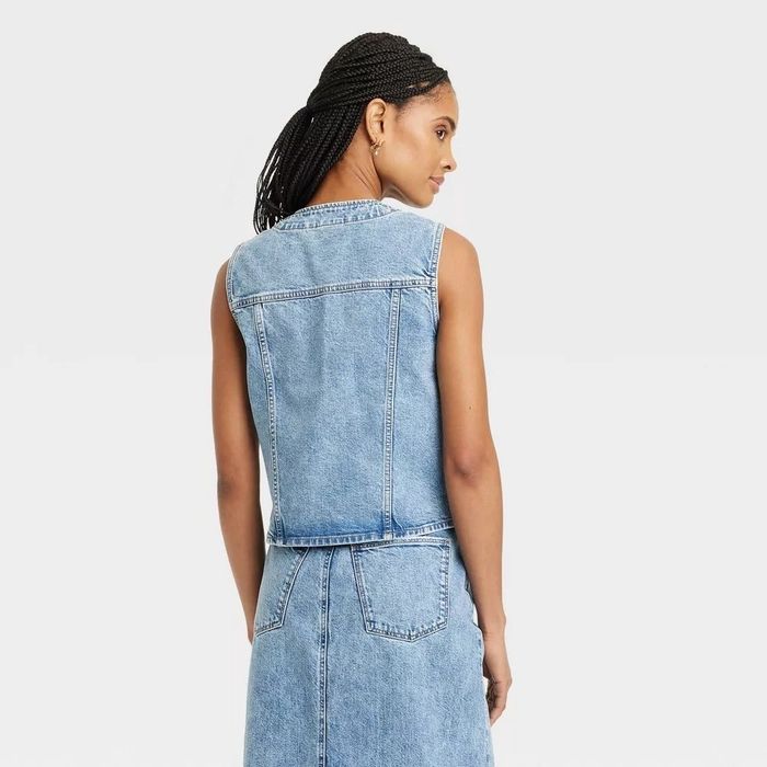 A person with braided hair wearing a sleeveless denim dress, with the back view captured.