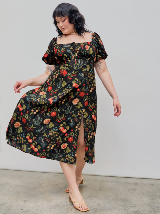 Model sporting a floral-print, short-sleeved, knee-length dress with a slit, paired with tan sandals, showcasing a relaxed yet stylish shopping outfit.
