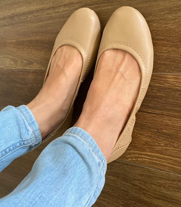 a reviewer showcasing tan flats paired with jeans