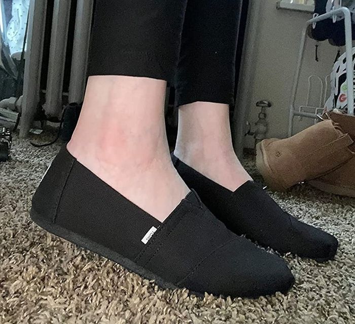 reviewer sporting black Toms canvas loafers