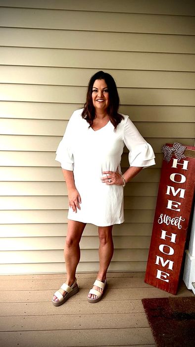 The reviewer is dressed in a white dress complemented by white sandals.