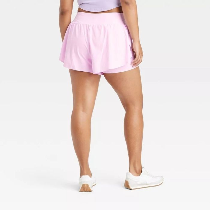 A person stands showing the back of pink running shorts and white athletic shoes—ideal for a fitness-themed shopping guide.