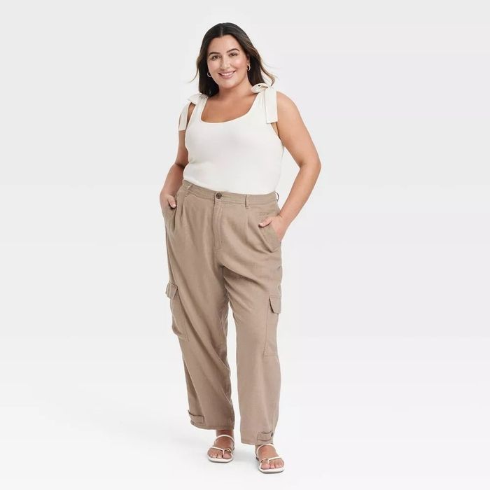 A person dressed casually in a white sleeveless top adorned with bow accents and beige cargo pants.