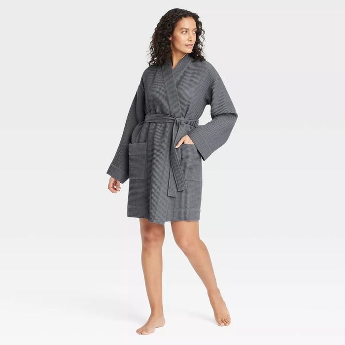 A person modeling a cozy, knee-length robe made from waffle-knit fabric, with long sleeves and a waist tie