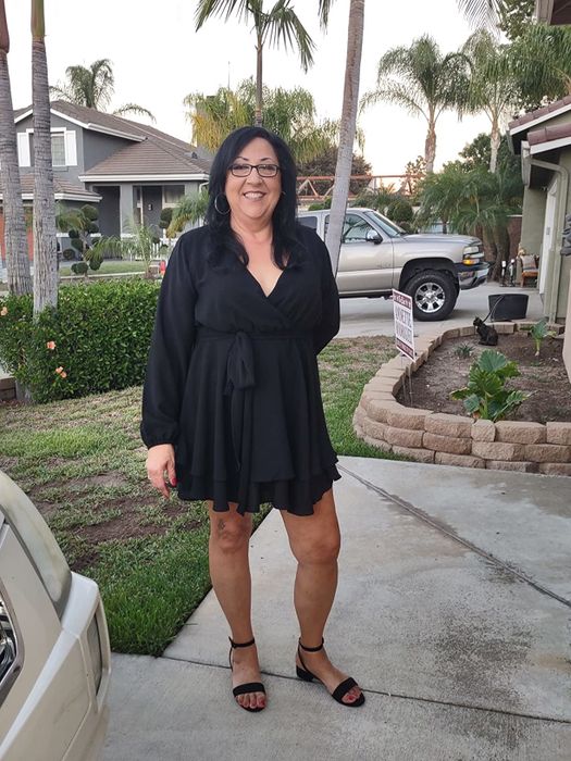 A reviewer showcasing black sandals paired with a black wrap midi dress
