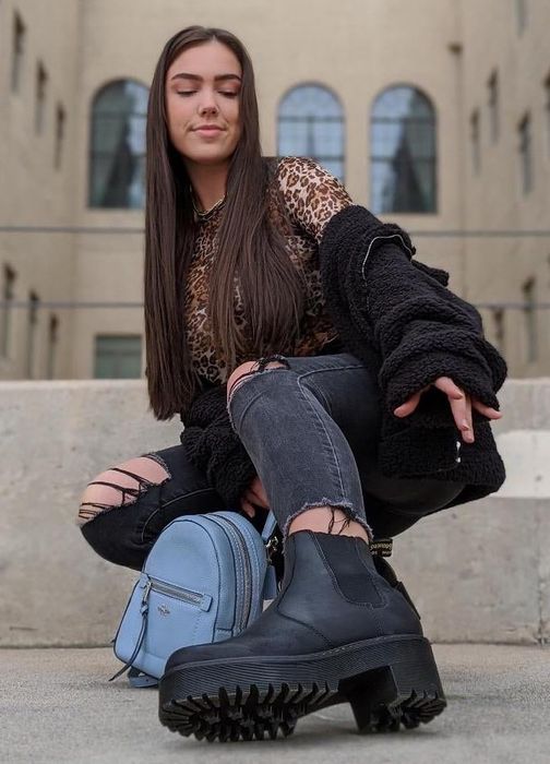 Close-up shot of the reviewer's foot, stylishly clad in black boots.
