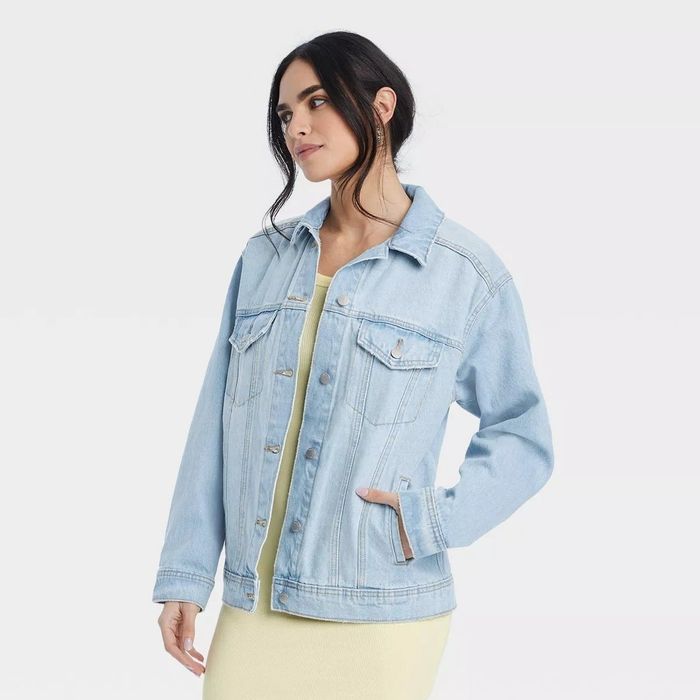 A model wearing a light-wash denim jacket over a light-colored dress.