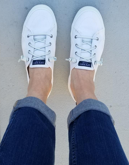 a reviewer’s feet in white sneakers