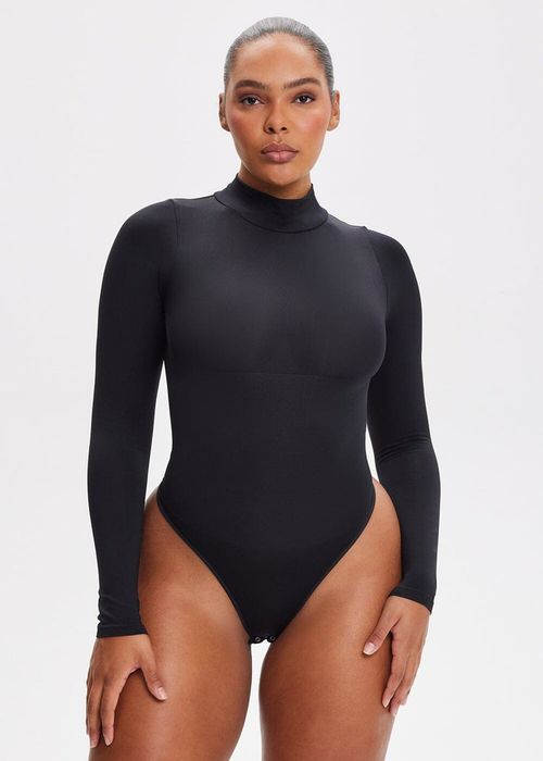 A model strikes a pose in a fitted long-sleeve bodysuit against a plain background, highlighting the sleek design and fit of the clothing.