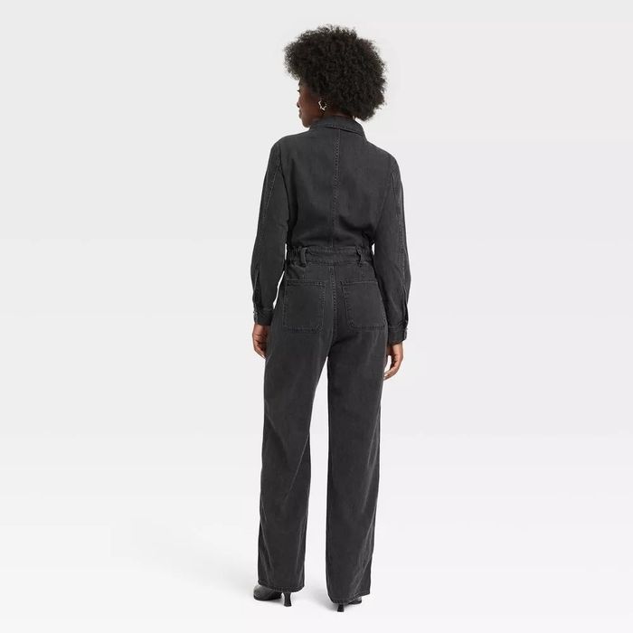 A person is seen from the back wearing a fashionable denim jumpsuit with long sleeves and wide-legged pants. This image is featured in a shopping article.