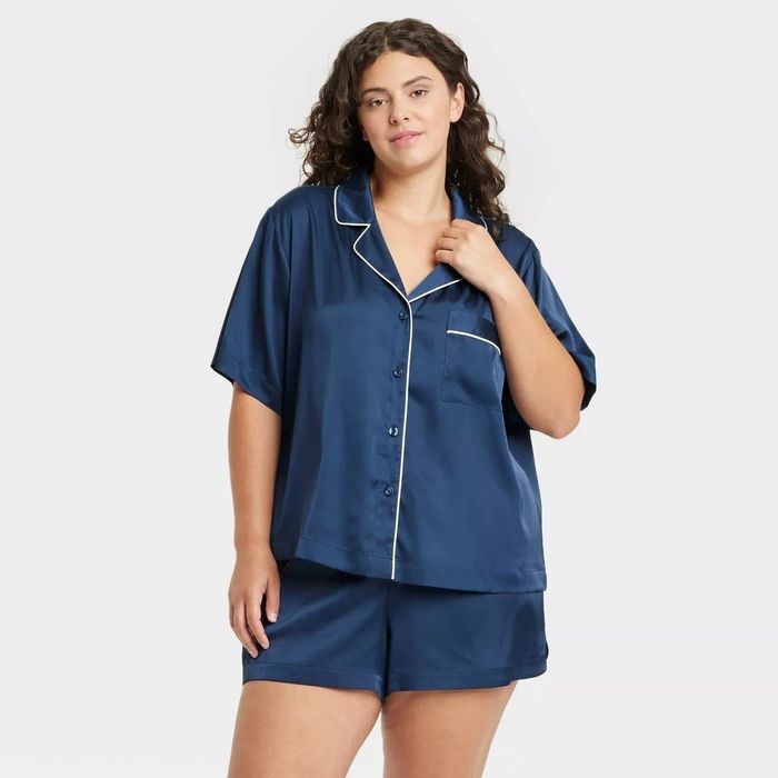 A model showcasing a satin pajama set with a button-up short-sleeve top and matching shorts
